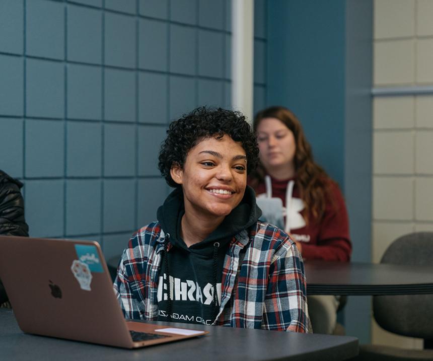 A student in a flannel shirt smiles in class